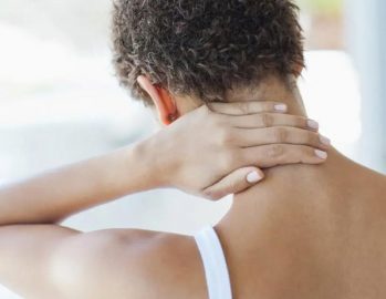Woman in pain rubbing back of neck